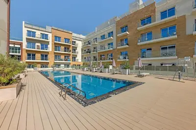a swimming pool in front of a building at Waves - Modern Studio Retreat W Pool & Gym Access in Dubai