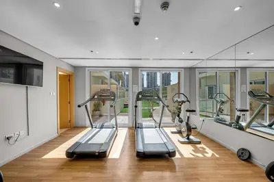 a gym with several treadmills and elliptical machines at Waves - Modern Studio Retreat W Pool & Gym Access in Dubai