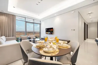 a dining room and living room with a table and chairs at Nobles Suites By Hostiva in Dubai