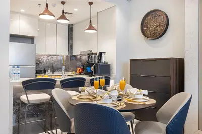 a dining room with a table and chairs and a kitchen at Nobles Suites By Hostiva in Dubai