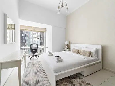 a white bedroom with a bed and a desk at Skyline Marina - Modern 2BR Retreat In Cayan-33 in Dubai