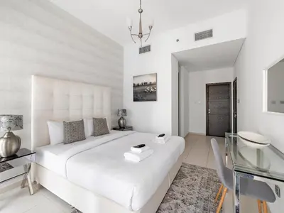 a white bedroom with a large bed and a glass table at Skyline Marina - Modern 2BR Retreat In Cayan-33 in Dubai