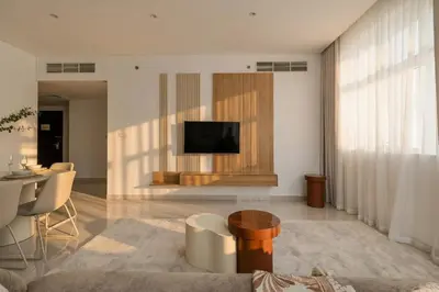a living room with a television on a wall with a table at 3 Bedroom Hotel Apartment with Gym, Spa and Pool in Dubai