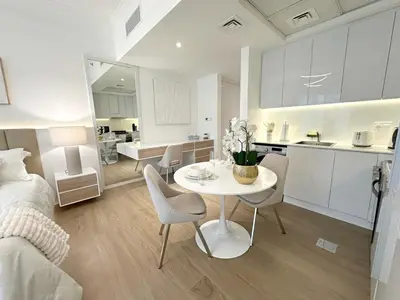 a room with a bed and a table and a kitchen at Brand New Studio Downtown, All Bills Included in Dubai