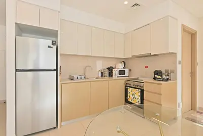 a kitchen with white cabinets and a white refrigerator at CH Skyline Bliss 1 BR near Burj Khalifa in Dubai