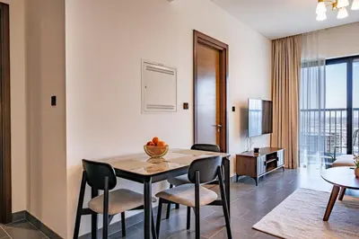 a dining room with a table and chairs and a living room at Brand New 1 Bedroom Apartment in Sobha Hartland Dubai in Dubai
