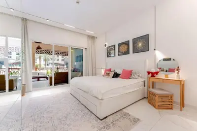 a white bedroom with a bed and a glass door at Luxury Apartment in Palm Jumeirah, Breathtaking Sea Views in Dubai