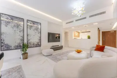 a white living room with a white couch and a tv at Luxury Apartment in Palm Jumeirah, Breathtaking Sea Views in Dubai