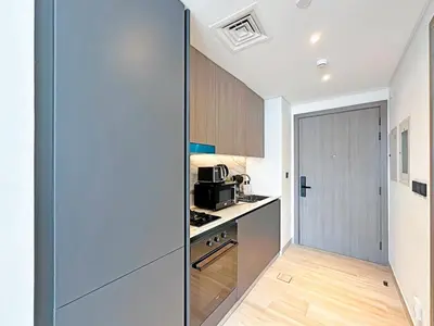 a kitchen with a door leading into a kitchen with a microwave at Stylish Contemporary Studio in Oxford Gardens in Dubai