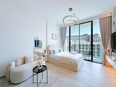 a white bedroom with a bed and a couch at Stylish Contemporary Studio in Oxford Gardens in Dubai