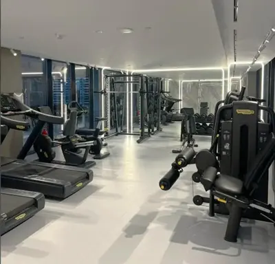 a gym with lots of treadmills and machines at Stylish Contemporary Studio in Oxford Gardens in Dubai