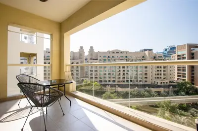 a balcony with a table and chairs and a large window at Spacious 1B in Palm Close to Palm Mall in Dubai