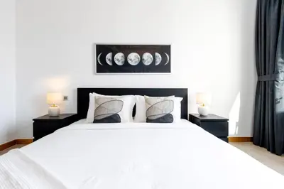a bedroom with a white bed with two night stands at Spacious 1B in Palm Close to Palm Mall in Dubai