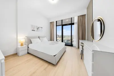 a white bedroom with a bed and a mirror at Elegant 1BR Near Downtown Azizi Riviera 3 in Dubai