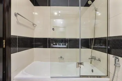 a bathroom with a tub and a glass shower at Chic Studio in JVC near Stadium and Miracle Garden in Dubai