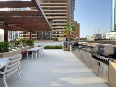 a rooftop patio with tables and chairs on a building at Homes Beyond l Marina Luxe 1BR at LIV in Dubai