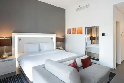 a bedroom with a large white bed and a couch at The First Collection Marina, Dubai, a Tribute Portfolio Hotel in Dubai