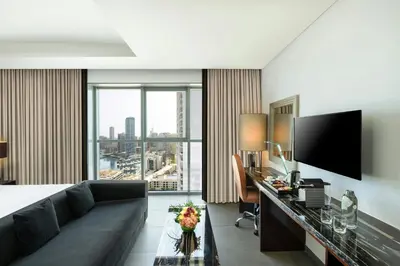 a hotel room with a couch and a desk with a television at The First Collection Marina, Dubai, a Tribute Portfolio Hotel in Dubai