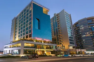 a tall blue building with cars parked in front of it at Ramada by Wyndham Dubai Barsha Heights in Dubai