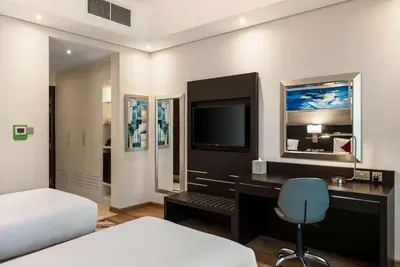 a bedroom with a desk with a tv and a bed at Ramada by Wyndham Dubai Barsha Heights in Dubai
