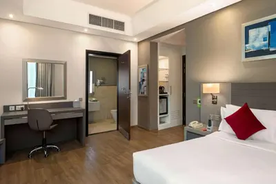 a bedroom with a bed and a desk and a bathroom at Ramada by Wyndham Dubai Barsha Heights in Dubai