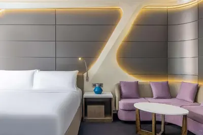 a room with a bed and a couch and a table at V Hotel Dubai, Curio Collection by Hilton in Dubai