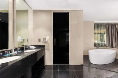 a large bathroom with two sinks and a large tub at V Hotel Dubai, Curio Collection by Hilton in Dubai