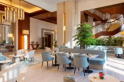 a restaurant with tables and chairs and a staircase at Hilton Dubai Al Habtoor City in Dubai