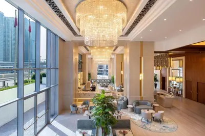 a lobby with a large chandelier and tables and chairs at Hilton Dubai Al Habtoor City in Dubai