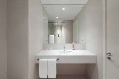 a white bathroom with a sink and a mirror at Rove Downtown in Dubai