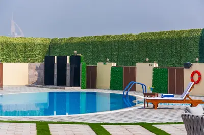 a swimming pool with a bench next to a hedge at MD Hotel By Gewan in Dubai