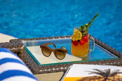 a drink and sunglasses on a tray next to a pool at La Suite Dubai Hotel & Apartments in Dubai