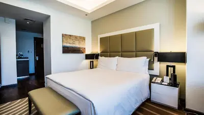 a hotel room with a large bed and a chair at La Suite Dubai Hotel & Apartments in Dubai