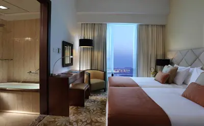 a hotel room with a bed and a bath tub at La Suite Dubai Hotel & Apartments in Dubai