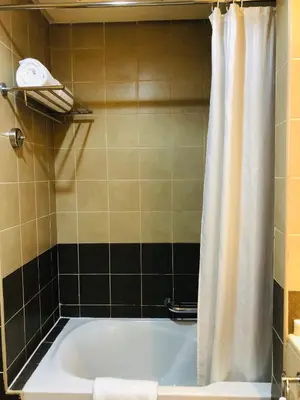 a bath tub with a shower curtain in a bathroom at Grand Bellevue Hotel Apartment Dubai in Dubai