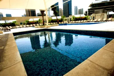 a large swimming pool with chairs and an umbrella at One Bedroom Apartment - Bay Central Tower in Dubai