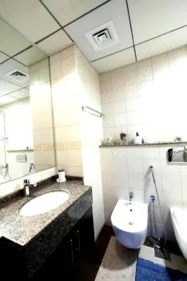 a bathroom with two sinks and a toilet and a mirror at One Bedroom Apartment - Bay Central Tower in Dubai