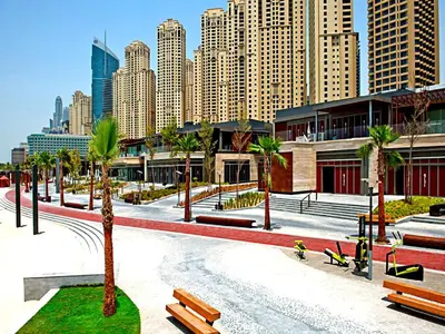 a park with benches and palm trees in a city at One Bedroom Apartment - Bay Central Tower in Dubai