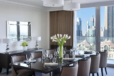 a dining room with a table and chairs and a large window at Kempinski The Boulevard Dubai in Dubai