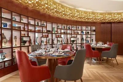 a dining room with tables and chairs and a wall of shelves at Shangri-La Dubai in Dubai