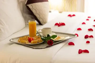 a breakfast tray with waffles and orange juice on a bed at Savoy Crest Hotel Apartments in Dubai