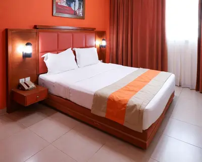 a bedroom with a large bed with orange walls at Wescott Plaza Hotel Apartments LLC Formerly West Zone Plaza Hotel Apts in Dubai