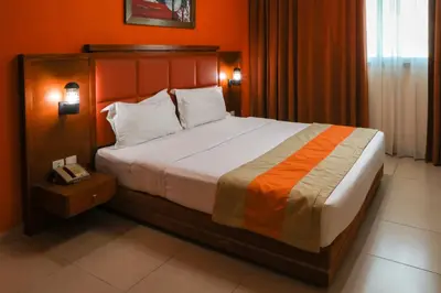 a bedroom with a large bed with an orange wall at Wescott Plaza Hotel Apartments LLC Formerly West Zone Plaza Hotel Apts in Dubai