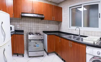 a kitchen with wooden cabinets and a sink and a stove at Wescott Plaza Hotel Apartments LLC Formerly West Zone Plaza Hotel Apts in Dubai