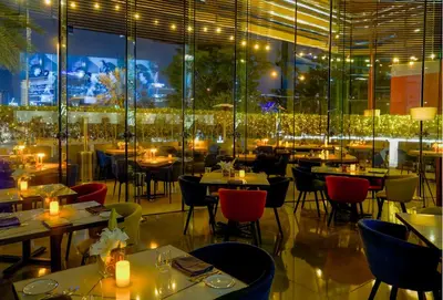 a restaurant with tables and chairs and a large window at Media One Hotel in Dubai