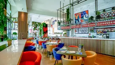 a restaurant with colorful chairs and tables and a bar at Media One Hotel in Dubai