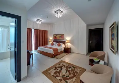 a bedroom with a bed and two chairs in a room at Marina Hotel Apartments in Dubai