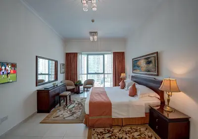 a bedroom with a bed and a desk and a window at Marina Hotel Apartments in Dubai