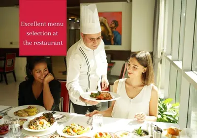 a chef holding a plate of food in a restaurant at Ramada by Wyndham Downtown Dubai in Dubai