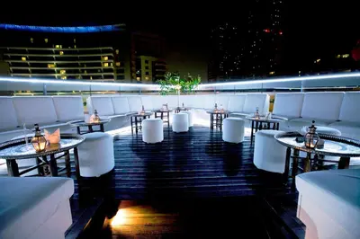 a restaurant with tables and white chairs on a rooftop at Social Hotel in Dubai